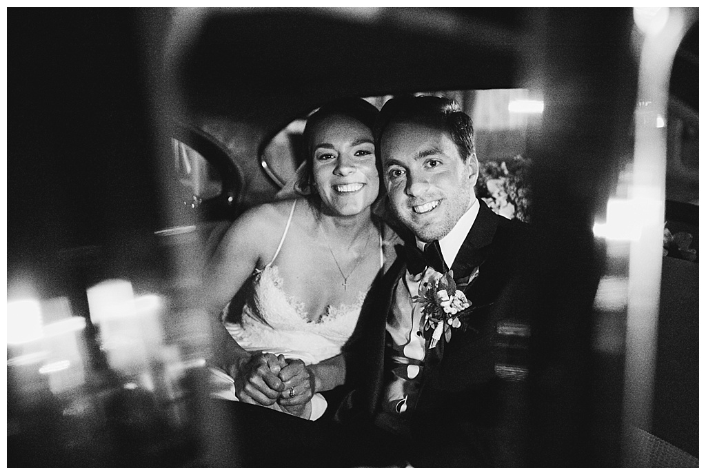 Bride and groom's final photo of the night in a vintage car